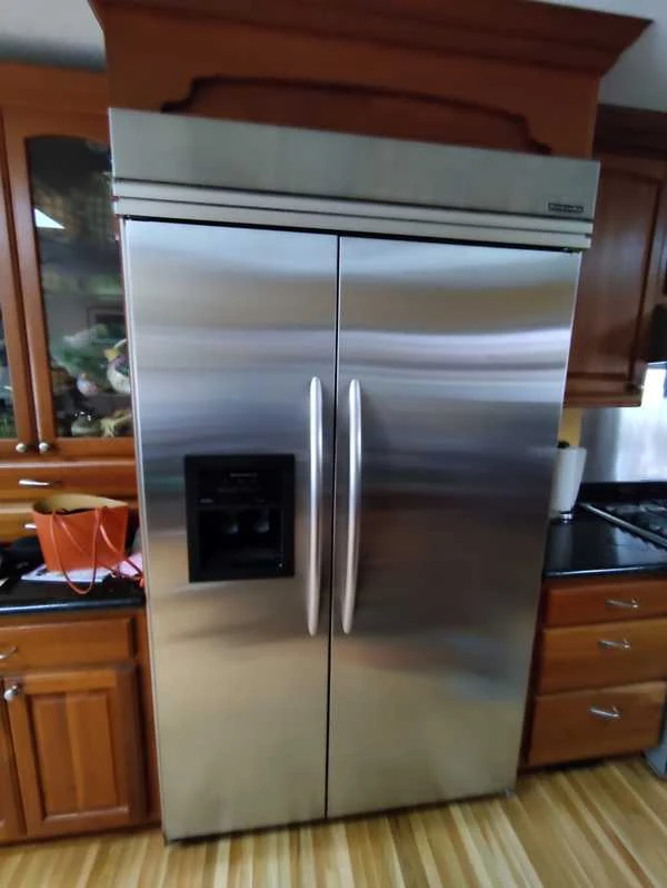 Stainless steel side-by-side refrigerator with an ice and water dispenser in the freezer door.